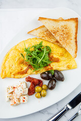 Breakfast of eggs with meat, herbs and drops of sauce with bread in a round plate top view
