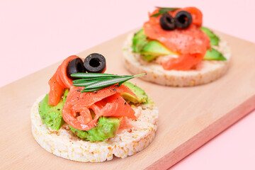 Rice Cake Sandwiches with Fresh Salmon, Avocado and Olives on Wooden Cutting Board. Easy Breakfast. Diet Food. Quick and Healthy Sandwiches. Crispbread with Tasty Filling. Healthy Dietary Snack