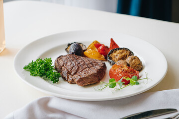 beef steak with grilled vegetables and herbs on a light background