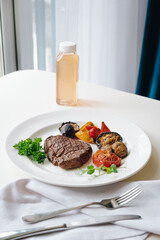 beef steak with grilled vegetables and herbs on a light background