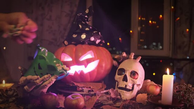 Carved pumpkin pointing with a finger at a bucket asking for candy and shaking it against the backdrop of Halloween decorations, stroking a skull among flickering garlands of candles and thick fog.