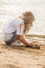 A girl plays with sand, a girl builds a castle from sand