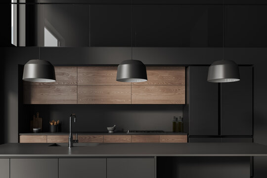 Dark home kitchen interior with cooking space, kitchenware on counter