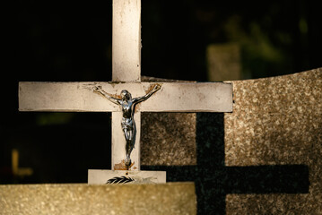 CEMETERY - An old crucifix with a figurine of Jesus on a tombstone
