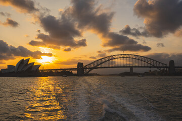 Cityscape image of Sydney, Australia with Harbour Bridge and Sydney skyline during sunset.
