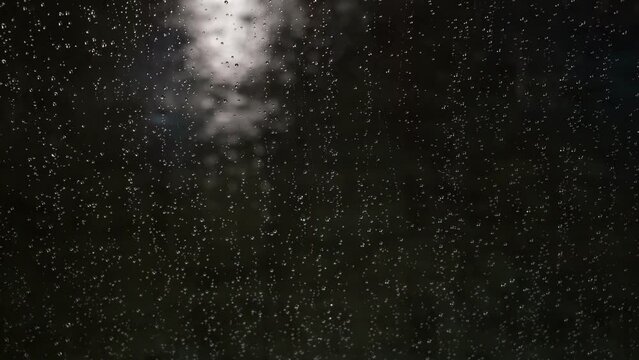 raindrops on car glass with blurred background and abstract lights at night