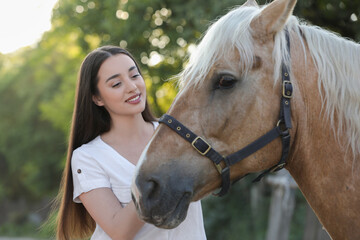 Beautiful woman with adorable horse outdoors. Lovely domesticated pet