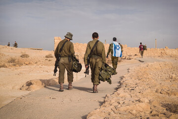 Back shot of several soldiers of israel army walking with israel national flag. Military man walking with other soldiers. War tactical exercise. infantry retreat from positions - obrazy, fototapety, plakaty