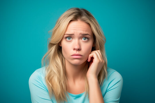 Mujer rubia con gesto de tristeza o aburrimiento ,con mano en el lado de la cara