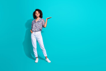 Full length photo of lovely positive girl dressed trendy clothes presenting empty space novelty news isolated on cyan color background