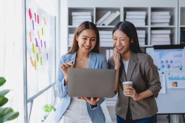 Two Asian businesswoman teamwork discussing and using laptop. Two Asian business women are talking and consulting.