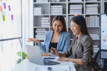 Two Asian businesswoman teamwork discussing and using laptop. Two Asian business women are talking and consulting.