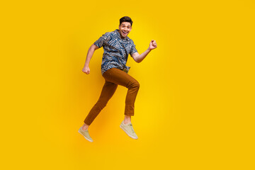Fototapeta na wymiar Full size photo of optimistic guy wear stylish shirt brown pants hurry run shoppping on black friday isolated on yellow color background