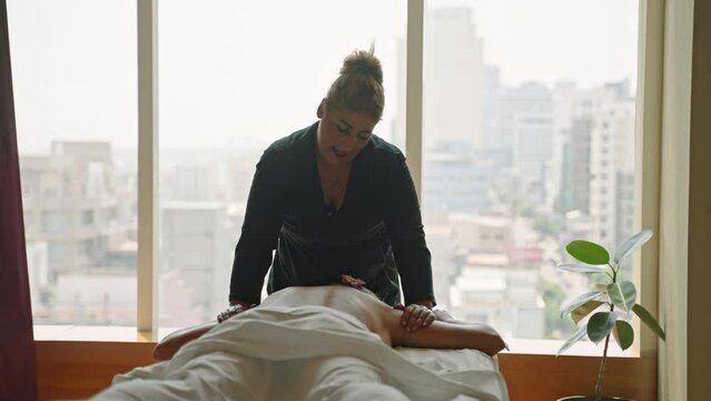 Woman masseuse in a luxury spa center does oil upper body massage to a young tanned client. Female wellness center employee performs a relaxing body care procedure to a girl, releases trigger points