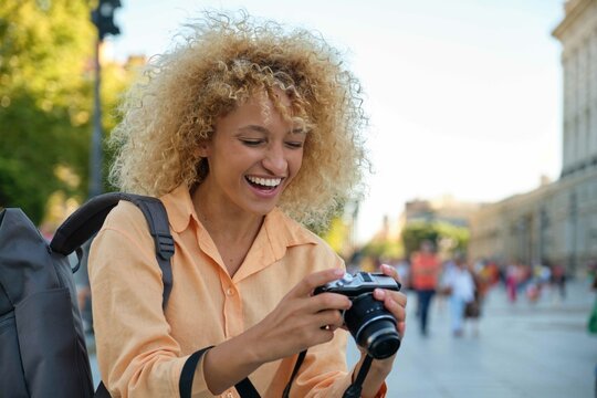 Latin female tourist smiling and looking at photos in her camera while sightseeing in Madrid, Spain.