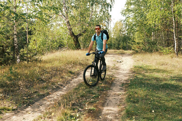 Fototapeta na wymiar active lifestyle.A man with a backpack rides a mountain bike through the autumn forest.Mountain Bike