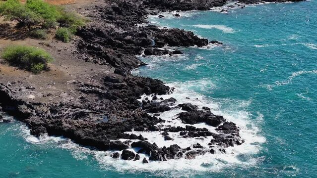Aerial coastal rocky shore beautiful waves beach Kona Hawaii. Big Island, largest, most volcanic active destination. Economy is tourism. Beautiful clear blue ocean sea. Rocky cliff. Waves and surf.