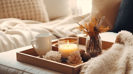 Still life details in home interior of living room. Sweaters and cup of tea with
 serving tray on a coffee table. Breakfast over sofa in morning sunlight. Cozy autumn or winter concept. - obrazy, fototapety, plakaty
