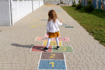 Junior schoolgirl playing hopscotch in school yard