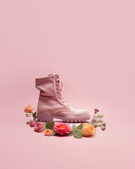 Combat boot arranged with colorful flowers, creative pastel pink composition, roughness and romance contrast
