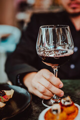 man hand holding a glass with red wine in a restaurant