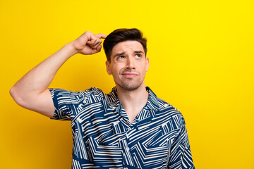 Portrait of minded doubtful person arm finger scratch head look empty space isolated on yellow...