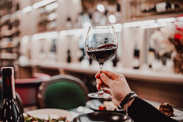man hand holding a glass with red wine in a restaurant