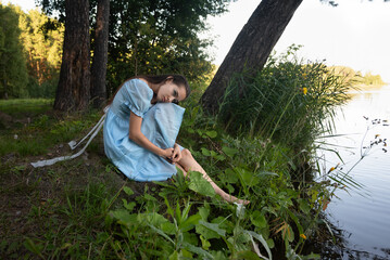 sad girl in a blue dress thinks about suicide by the lake