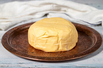 Butter in a copper plate. Organic fresh cow butter on wood background. Close up