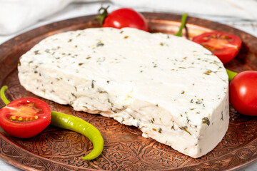 Herb cheese on a copper plate. Slices of herbed cheese on wooden background. local name otlu peynir. Close up