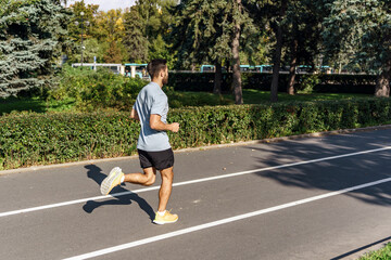 Obraz premium Warm-up running for an active workout, a young guy is an athlete. A man stretching his body outdoors taking care of his health.