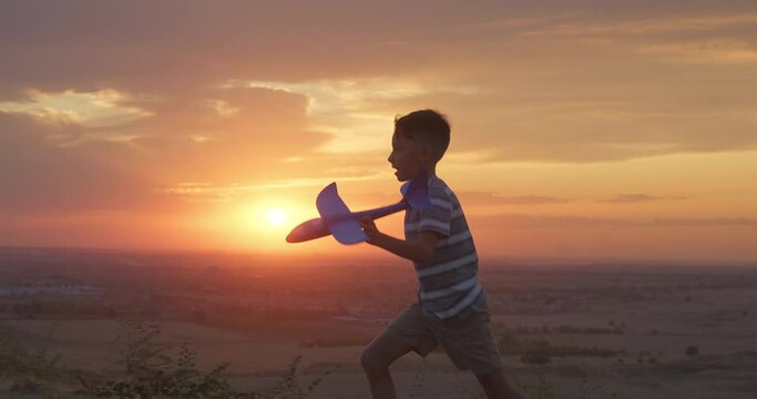 Kid run in nature with toy airplane at sunset. Happy toddler boy playing in nature. Happy family childhood concept