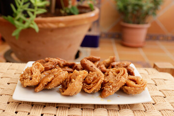 Moroccan chebakias on a white plate in a patio with plants
