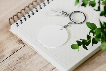 Round shape keychain with tassel on spiral notebook mockup. 3D rendering - obrazy, fototapety, plakaty