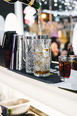Bartender pouring alcohol from the bottle preparing a Negroni. Close-up