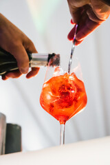 Process of preparing an Aperol spritz wine cocktail prosecco close-up at a bar counter