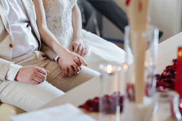 Bride and groom holding hands on their wedding day closeup