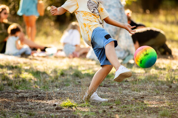 Boy playing with a ball in the park with his friends in the background