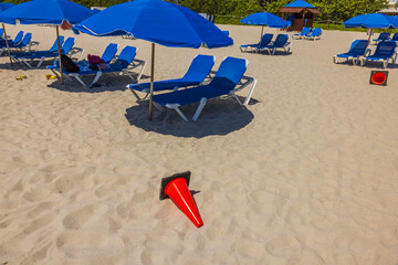View of groups of blue sunbeds beneath sun umbrellas on Miami Beach. Miami, Florida, USA. 