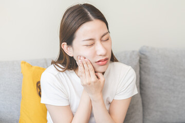 Closing eyes asian young woman hand touching cheek, face expression from toothache, tooth decay or sensitivity, Having tooth or teeth problem or inflammation, suffering from health. Sensitive teeth.