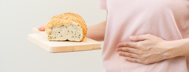 Gluten allergy woman hand holding, refusing to eat white loaf slice on board in breakfast food meal at home, girl having a stomach ache. Gluten intolerant and Gluten free diet, isolated on background. - obrazy, fototapety, plakaty