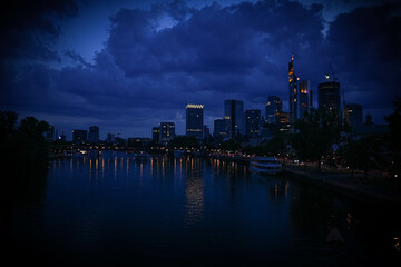 the skyline in frankfurt am main at night. panorama picture from a bridge over a big river. main...