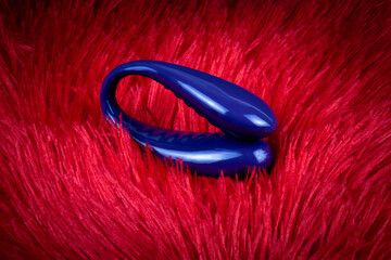 Sex toy, vibrator. On a red velvet background.