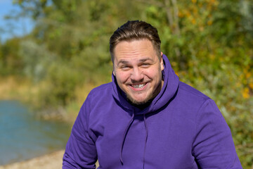 Young attractive man wearing a purple hoodie laughing funny