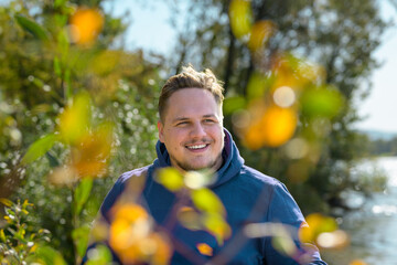 Portrait of a attractive man wearing a purple hoodie behind some bushes