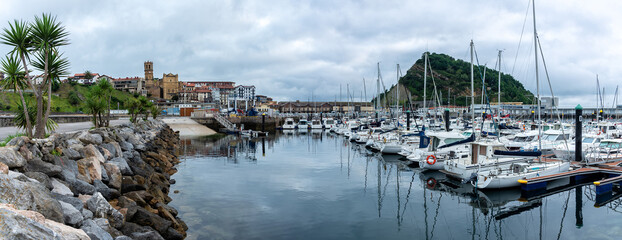 Obraz premium Panoramic view of Getaria fishing port with the old town on one side and Mount San Anton on the other on a cloudy day, Gipuzkoa, Basque Country, Spain
