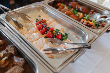Delicious salmon garnished with tomatoes in a silver tray as part of a buffet at a wedding
