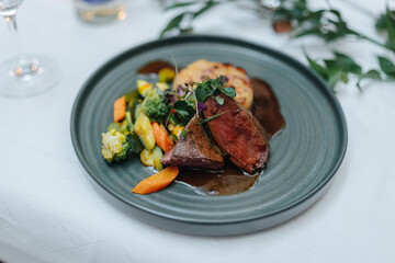Gourmet roast saddle of venison with vegetables and potato gratin at a wedding dinner in Germany