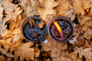 Two glass glasses with mulled wine stand on yellow autumn foliage
