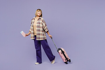 Traveler woman wear beige casual clothes hold bag passport ticket look aside isolated on plain purple background. Tourist travel abroad in free spare time rest getaway Air flight trip journey concept